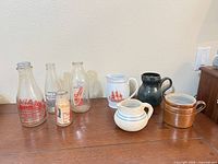 Group shot of all bottles, porcelain pitcher and stoneware pieces on table