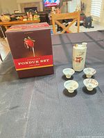 Fondue set box front with strawberry image; sake flask and cups beside