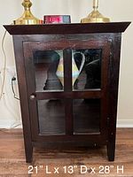 Front view of wood nightstand cabinet with glass door showing ceramic pitcher inside