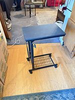 Full view of side table showing metal frame, top surface, caster wheels and basket shelf