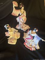 Three geisha figurines on black backdrop