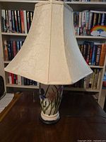 Full view of lamp on table, showing shade and ceramic base