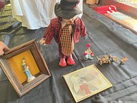 Group shot of clown doll, shadow box, print and three mini clown pieces