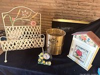 Group shot showing all four items: metal rack, gold wastebasket, floral clock, wood cabinet