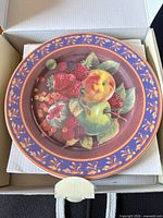 Top view of one plate showing fruit design and rim pattern inside box