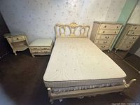 Full view of bed frame, mattress, nightstand, side table and tall chest