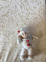 White porcelain clown figurine with polka dots and red pom-poms