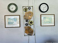 Full view of wall arrangement showing sculpture, two prints, analog clock, thermometer