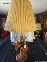Full view of lamp showing wooden base, four bulbs with glass chimneys, pleated shade