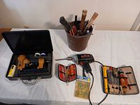 Overall lot showing drill, nailer case, bucket of hand tools, zippered toolkit, bit set and screws