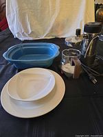 group shot of blue baking dish, white plates and bowl, and stainless espresso maker with power cord