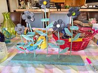 Metal flower stand and surrounding objects including iridescent glass egg visible left side