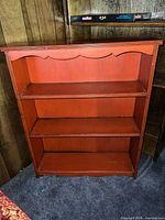 Front view of orange/coral distressed bookshelf with three shelves