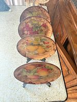 Four decorative plates on easels showing fruit designs