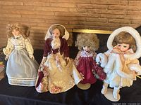 All four porcelain dolls on stands displaying full attire