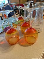 Upside-down view of ombre and floral wine glasses plus clear glass pitcher