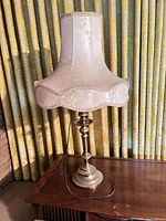 Full view of brass-finish lamp with fabric shade on table