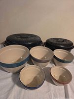 Group shot of both roasters with lids and five ceramic bowls