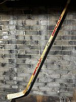 Full length view of Graf Fusion 3050 wooden hockey stick leaning against wall