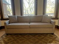 Front view of grey fabric pull-out sofa bed showing cushions, arms and legs