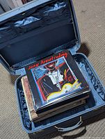 Open blue suitcase filled with vinyl LPs, Joan Armatrading The Key visible on top