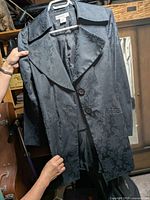 Full view of Nine West black damask patterned coat on hanger