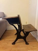 Side profile showing wood seat, desk top and cast iron frame