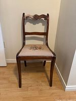 Front view of brown wood side chair with beige floral needlepoint seat