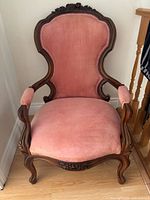 Front view of armchair showing upholstery and carved frame
