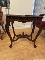 Side view of carved wood side table showing floral apron and cabriole legs