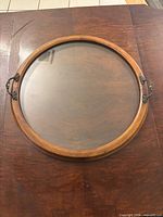 Round wooden serving tray with glass insert and brass handles