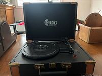 Turntable open showing platter, tonearm, and logo inside lid