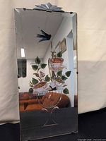 Front view showing painted floral motif, bird, etched vase, metal crest