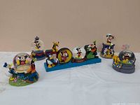 Front view of six Walt Disney Parks snow globes featuring Mickey Mouse, Minnie Mouse, Donald Duck, Goofy and Pluto
