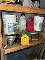 Shelf with two Walter buckets, sprayer, watering can, birdhouse, funnel, plant stand, saucers