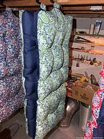 Front view of hanging tufted outdoor cushions showing paisley pattern and navy edges