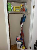 Closet view showing sweepers, mop, bucket with contents, upper shelf cleaners