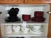 Cupboard shelf with black, burgundy and white dish sets