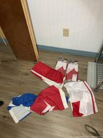 Group of five flags on floor, two packaged Canadian flags, two loose Canadian flags, one blue and white flag