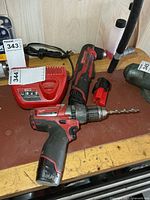 Both drills, charger and one battery on workbench