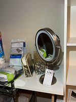 Vanity mirror, shower hooks, towel stand, mesh bag visible on shelf