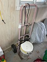 Full view of pink steel hand truck with bucket attached