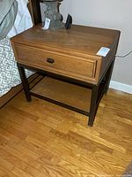 Front angled view of nightstand showing drawer, metal base and lower shelf
