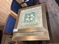 Two square framed floral prints stacked, showing gold frames and floral artwork