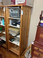 Front view of tall solid wood cabinet with door open, showing shelves and natural finish