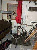 Full umbrella standing, closed, showing pole and red canopy