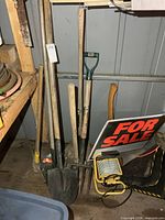 Group of handled yard tools, sign, work light