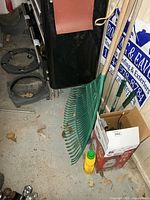 Green plastic rake, plant dollies, sprayer box visible