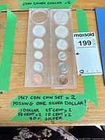 Two plastic holders showing both coin sets on table with green tape notes