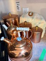 Group view showing copper kettle and three copper canisters with lids